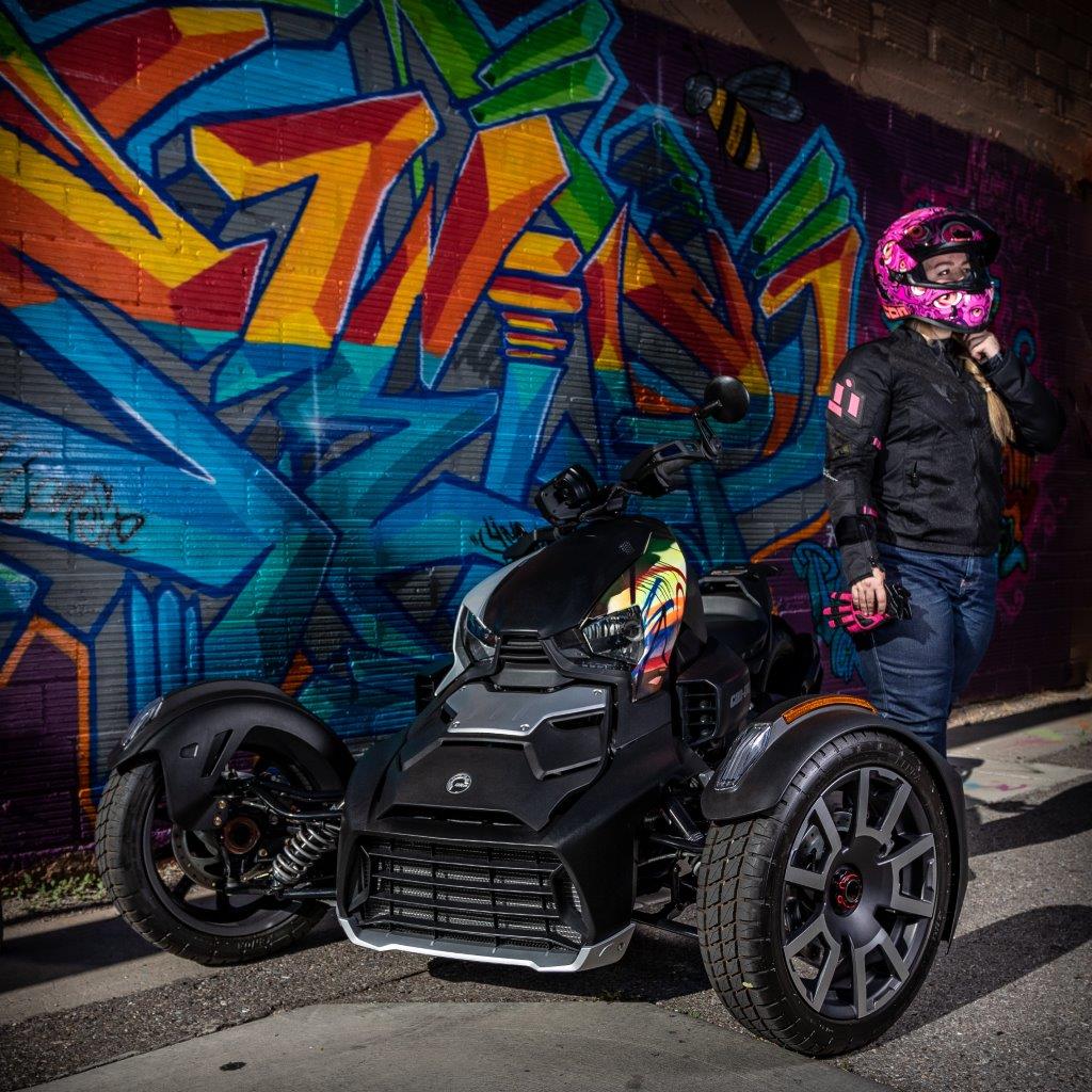 Female rider standing next to Can-Am motorcycle