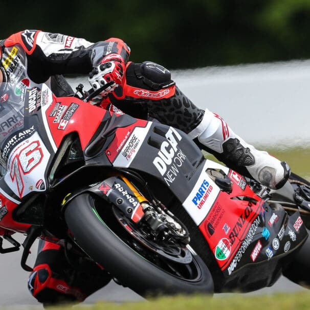 A front view of Loris Baz at the MotoAmerica Superbike Championship, leaning into a turn.