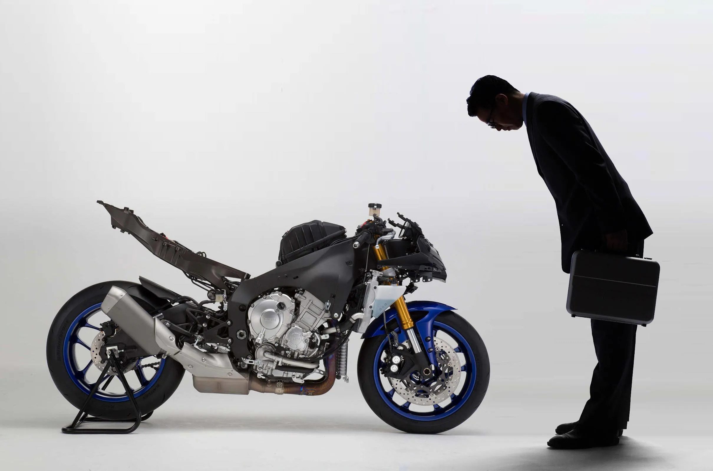 a picture of a businessman bowing to a dismantled motorcycle from Yamaha
