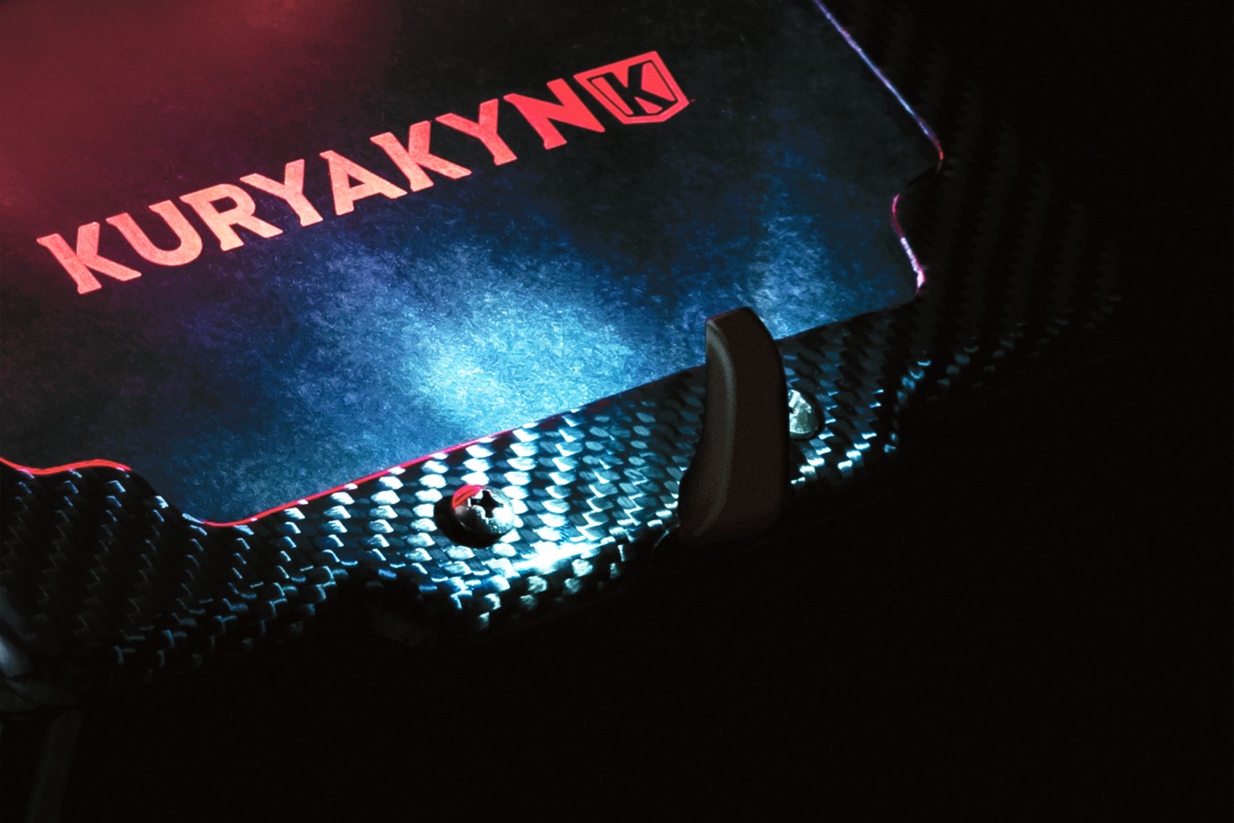 A view of a part highlighted in dramatic lighting, sporting the Kuryakyn brand name. 