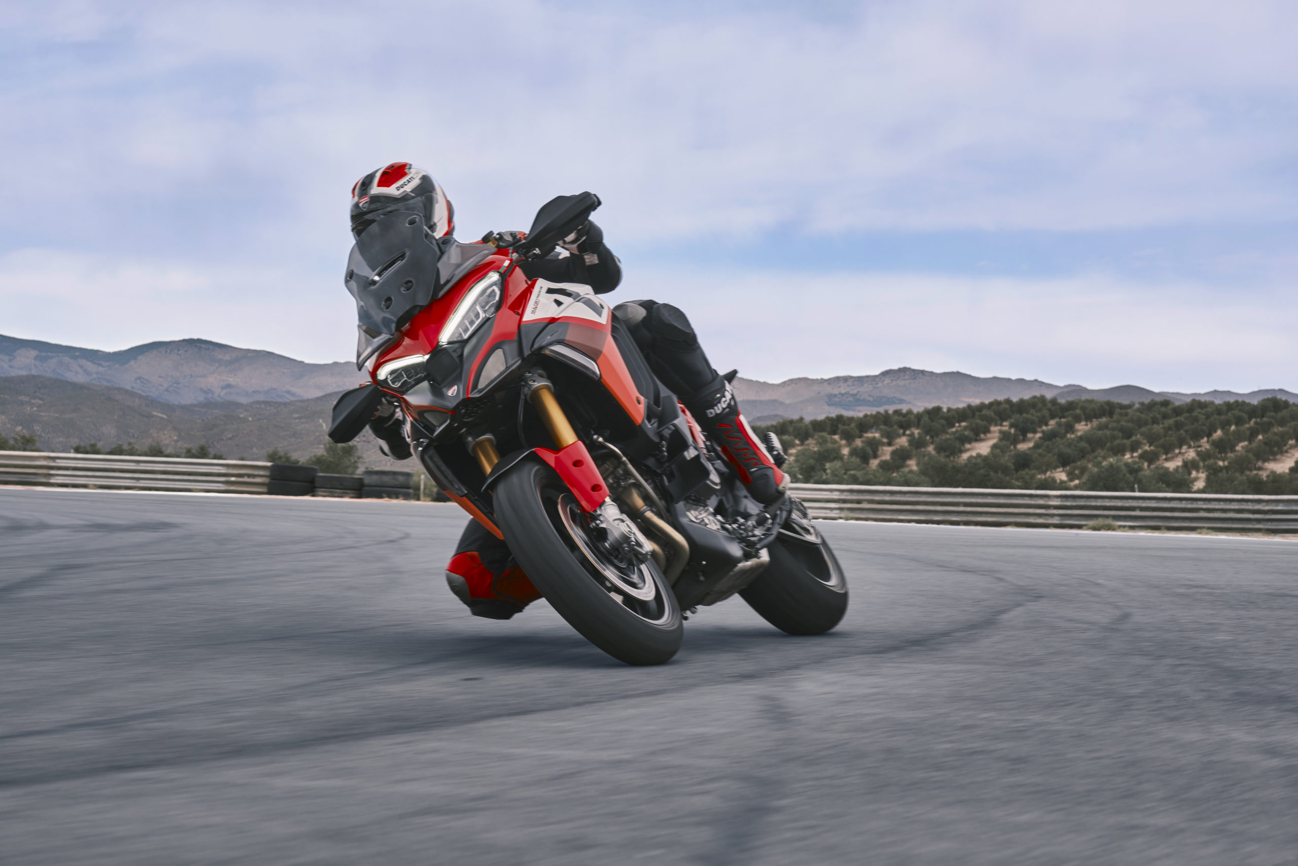 A side view of the new Multistrada V4 Pikes Peak from Ducati - the third motorcycle to be debuted in their World Premiere series. Media shows a rider sitting on the Pikes Pkea with clouds in the background