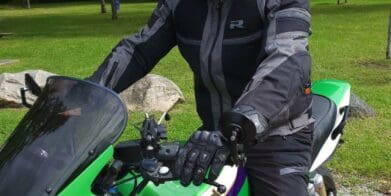 Man wearing Richa Airstorm WP Jacket while sitting on green Kawasaki motorcycle