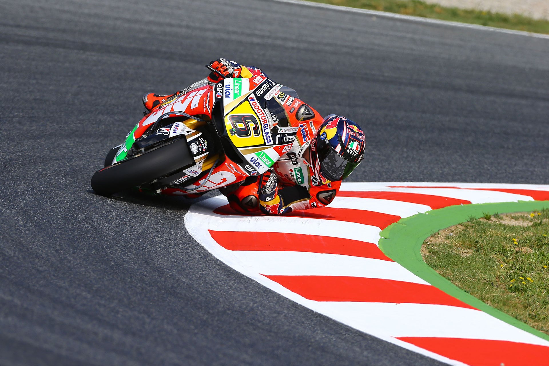 a rider takes a corner on a MotoGP circuit at an extreme lean angle