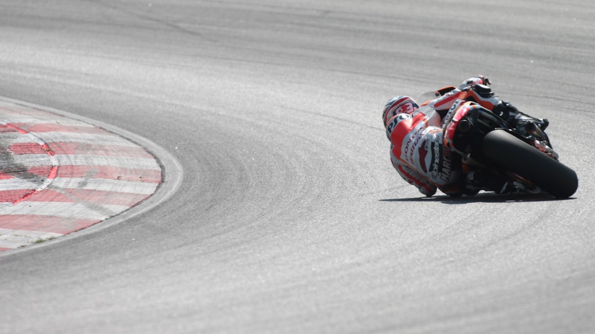 Marc Márquez takes a corner on a MotoGP circuit at an extreme lean angle