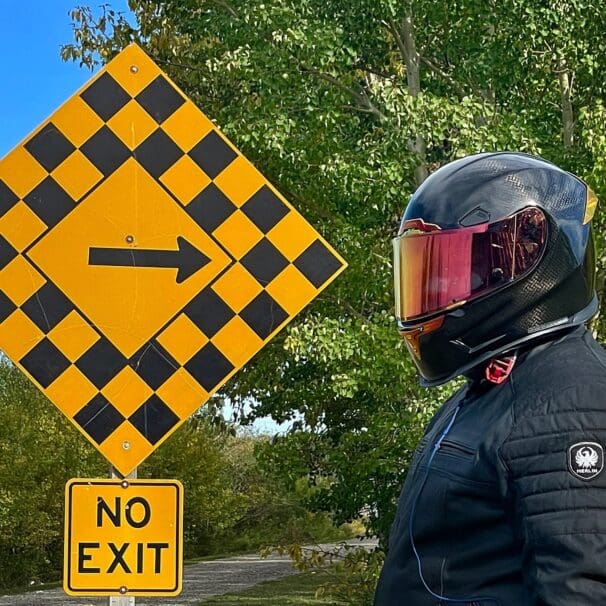 Author wearing Icon Airframe Pro Carbon Helmet and standing next to road sign