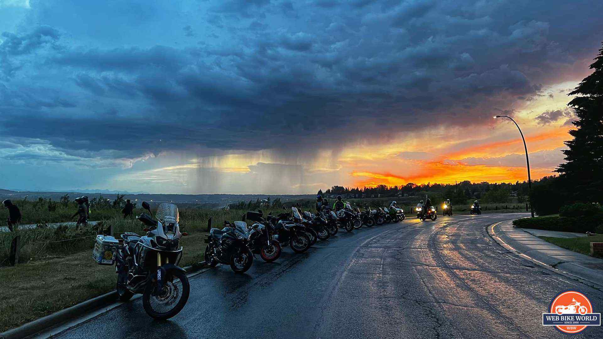 Motorcycles parked under grey clouds at sunset