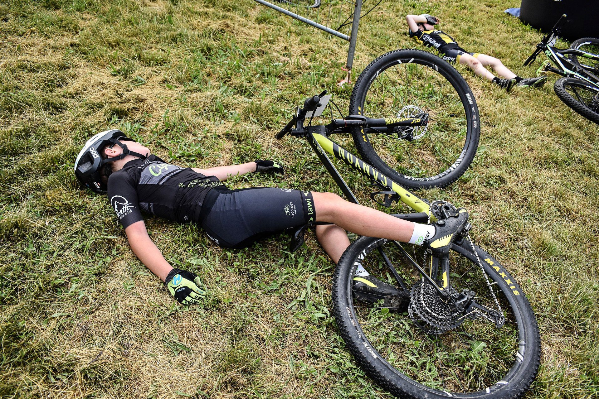 Exhausted young cyclist collapses on grass after race