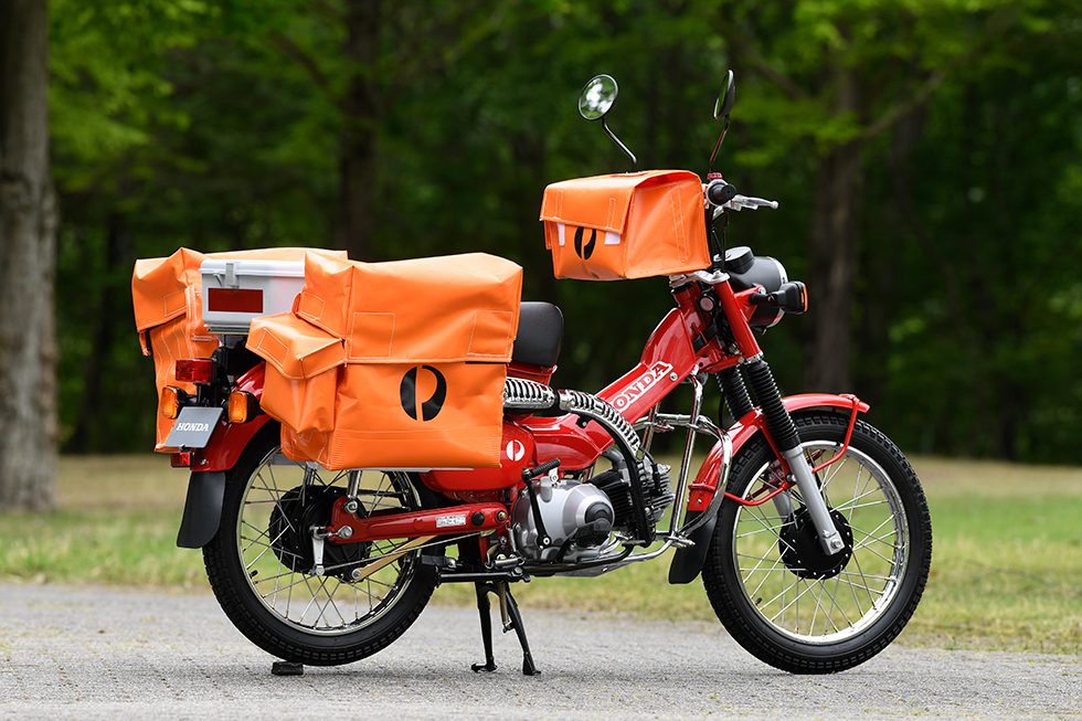 A Honda CT110 'Postie' bike with mailbags in a park