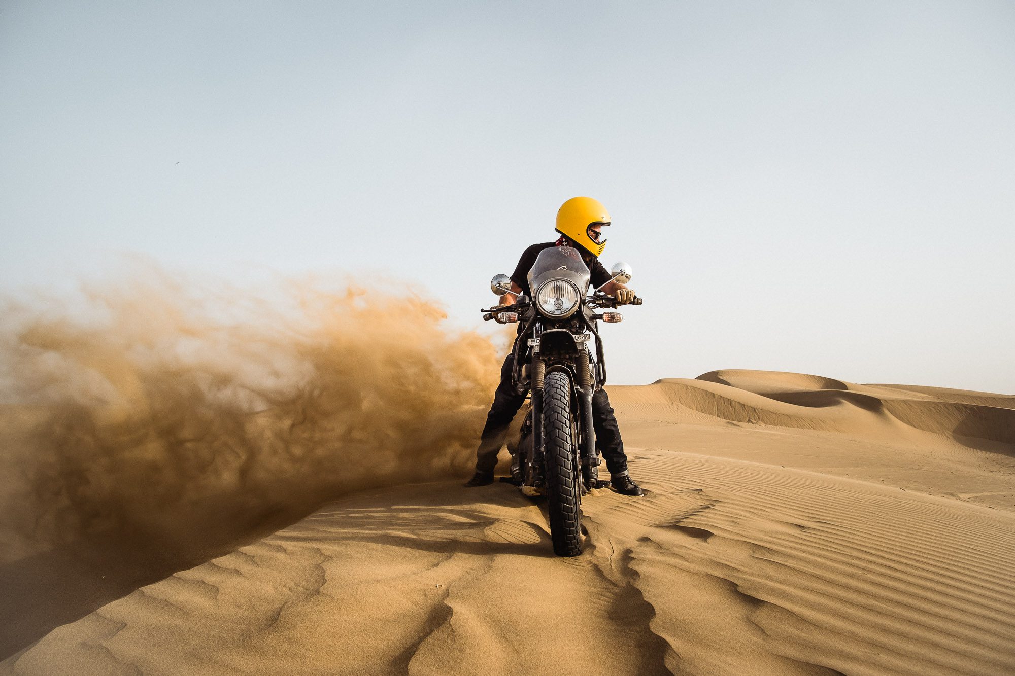 A royal Enfield rider creates a 'rooster tail' in the Rajasthan desert