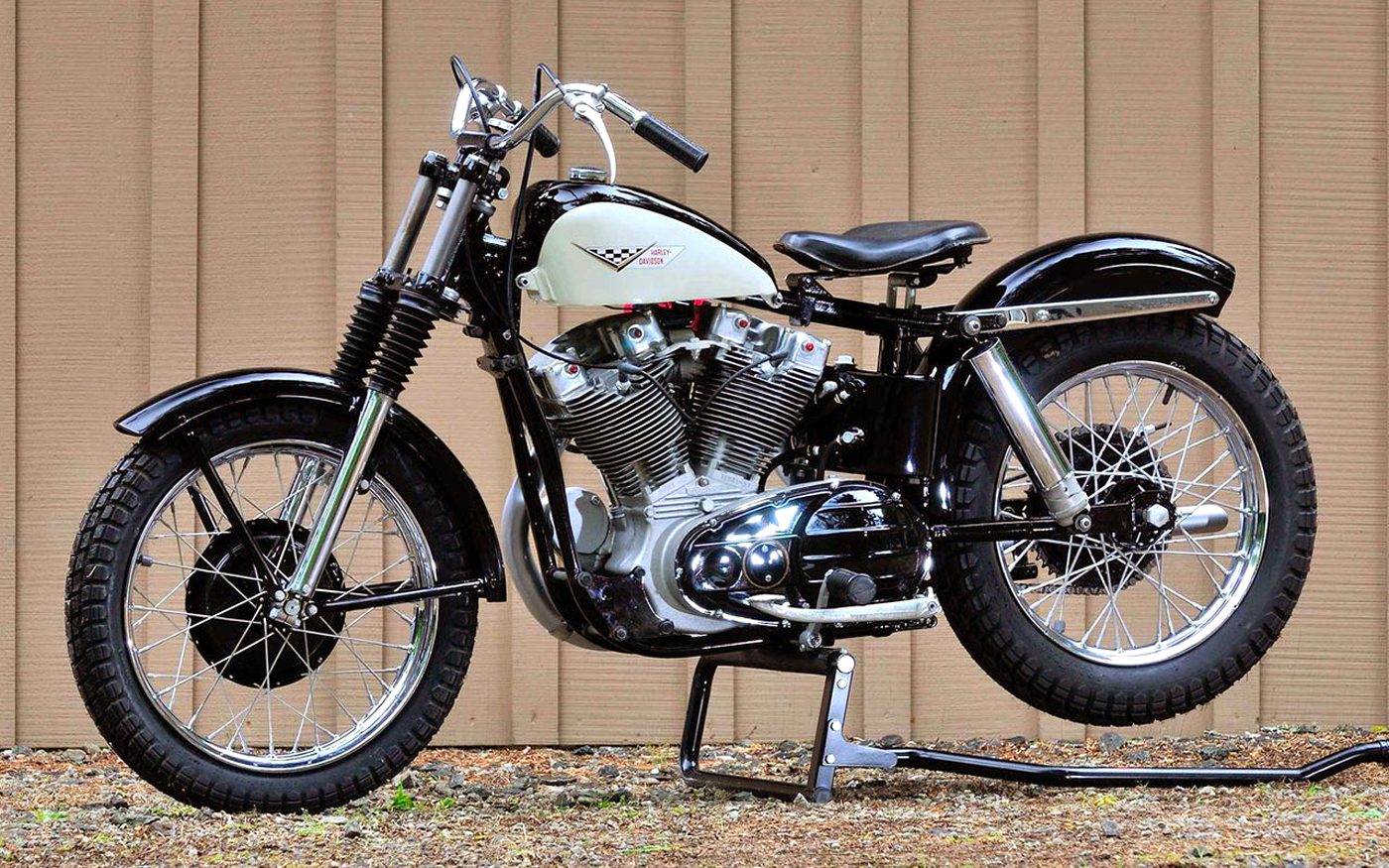 A classic Harley-Davidson Sportster motorcycle from the 1950s is park by a wooden fence in the USA