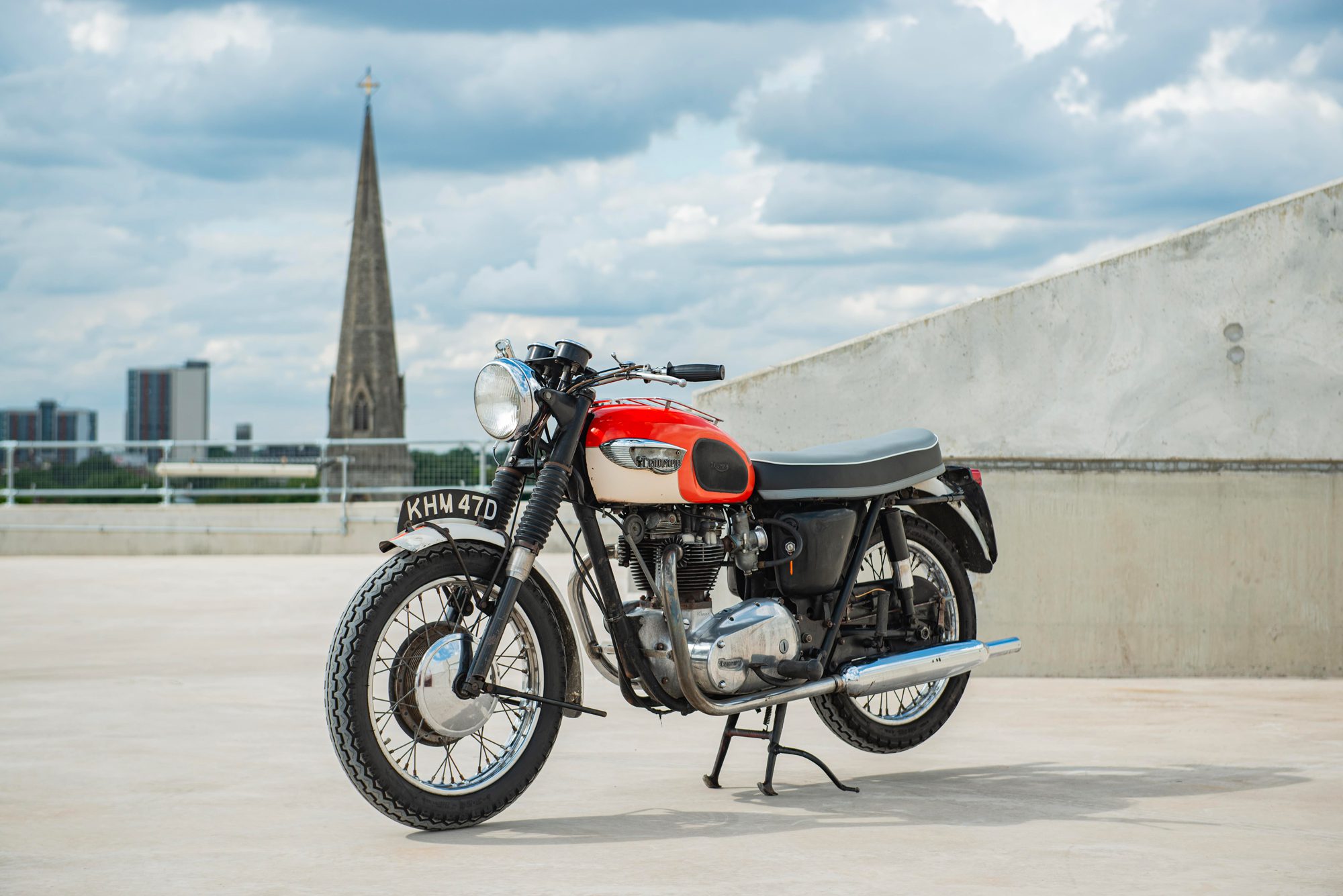 a 1966 Triumph Bonneville motorcycle in orange on a UK rooftop