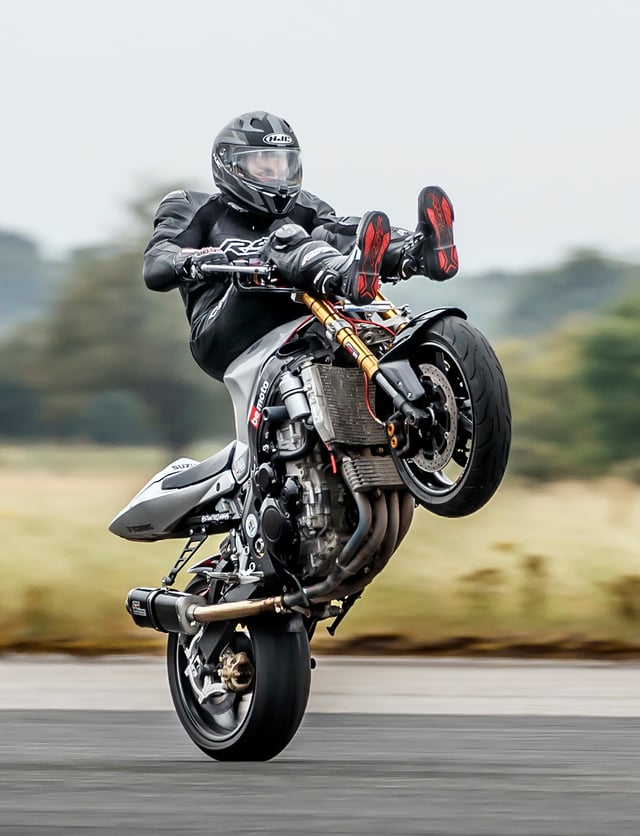 A motorcyclists performs a wheelie on a motorcycle