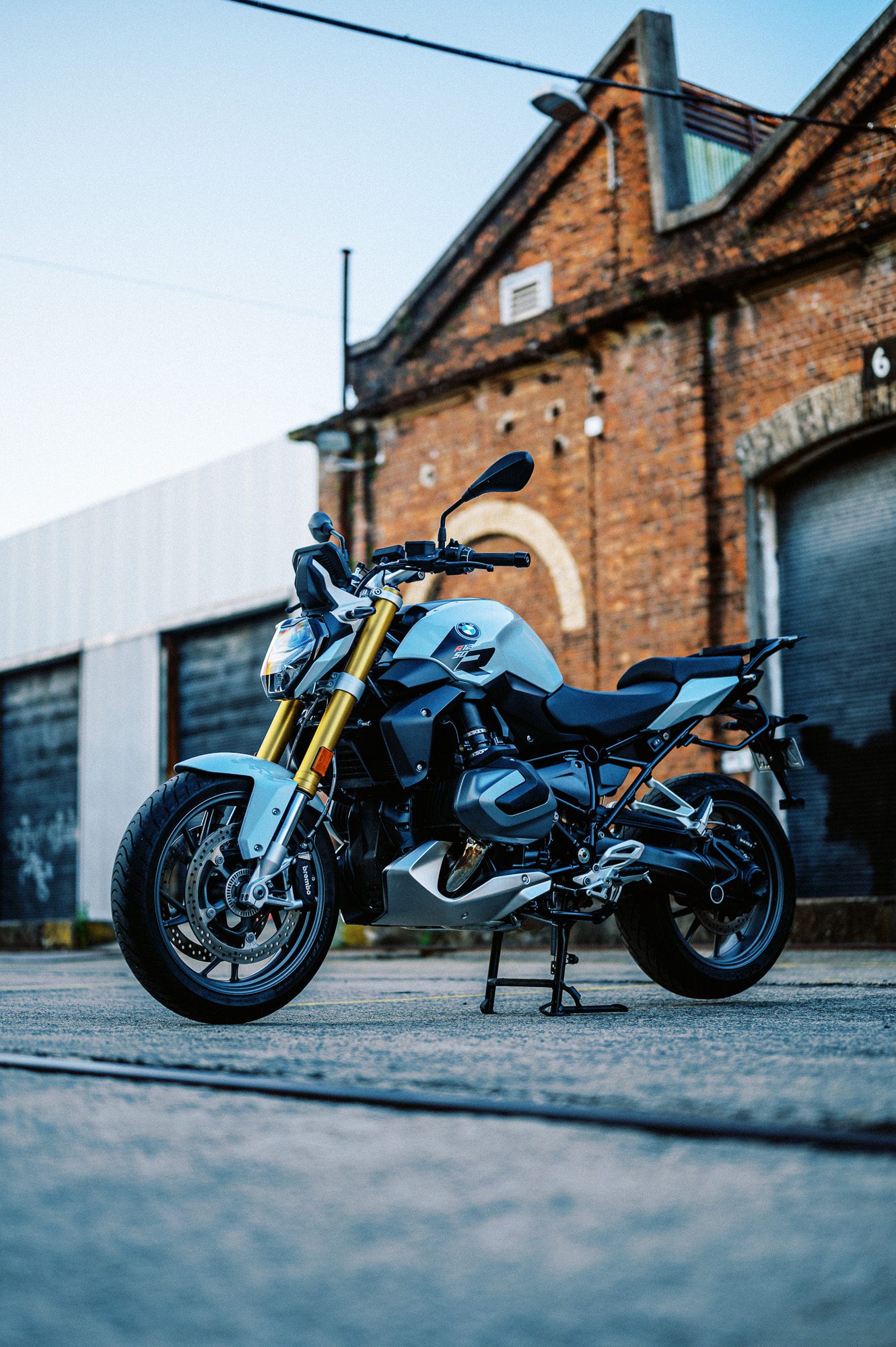 a photo of a 2023 BMW R 1250 R motorcycle at dusk in an old train carriage works