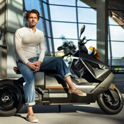 BMW's new Design Director, Alexander Buchan, sitting on one of his designs, the CE 04. Media sourced from BMW.